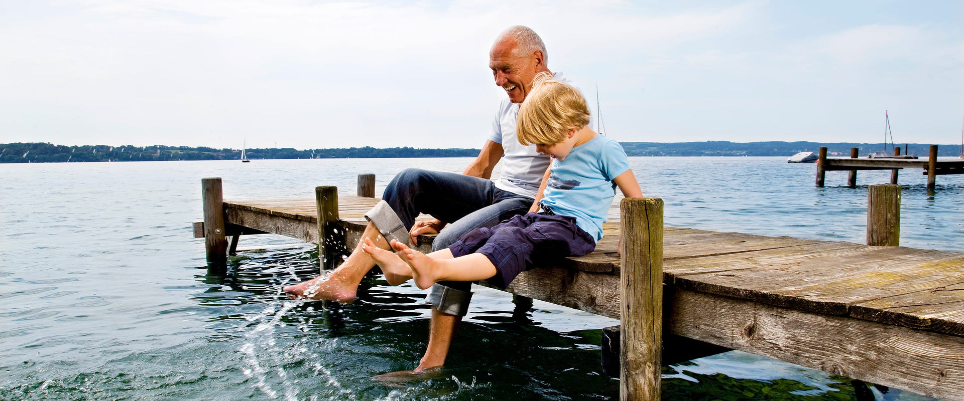 Grandparent and child on dock next to water
